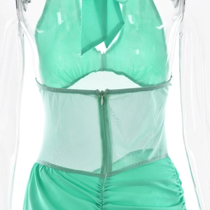 Detail of mint green halter dress showing mesh splice, pleated fabric, and invisible zipper