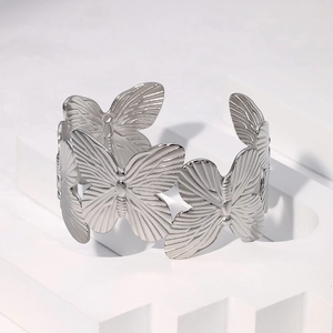 Macro shot of silver butterfly textured hollow metal cuff bracelet on stone pedestal
