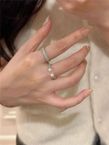 Detail of silver rings featuring minimalist pearls and pavé cubic zirconia on hand