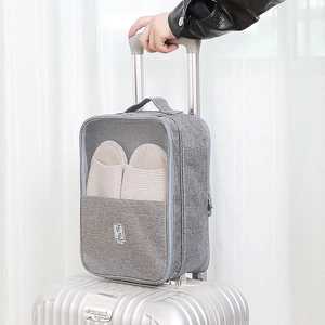 Gray travel shoe storage bag attached to silver luggage handle with breathable mesh panel