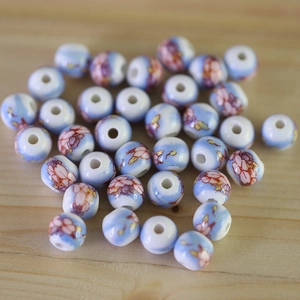 Detailed macro view of hand-painted blue and white ceramic beads with pink floral patterns