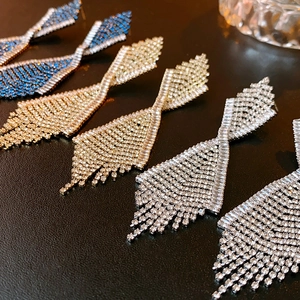 Nahaufnahme der geometrischen Quasten-Ohrringe mit Strasssteinen in Blau, Gold und Silber