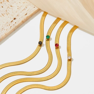 Flat gold snake chain necklace with multicolored zircon stones on beige stone and silk