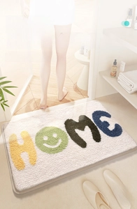 Dettaglio del tappeto da bagno floccato ad alta densità con design Home e smile