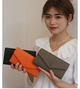Detailansicht von Leder-Umschlagbrieftaschen in Schwarz, Orange und Taupe-Texturen