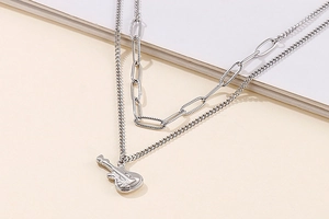 Detail view of a layered silver guitar pendant necklace featuring textured oval link chains