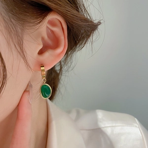 Gros plan de boucles d'oreilles vintage avec pendentif en résine vert émeraude et anneaux dorés