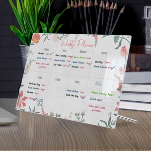 Detailed view of an acrylic weekly planner on wooden desk with floral pattern and metal stands