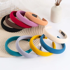 Flat lay of colorful padded headbands with pearls on a woven mat in natural light