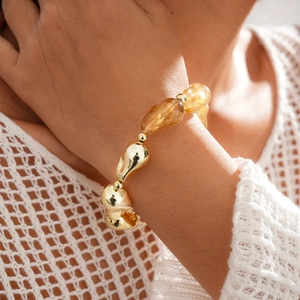 Détail de perles en résine ambrée et de perles dorées irrégulières sur un bracelet