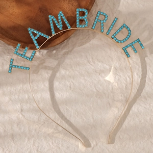Golden Team Bride headband with blue rhinestones on beige fabric background