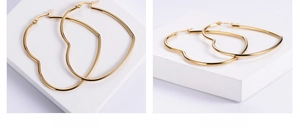 Detailed view of polished heart-shaped gold hoop earrings on a white minimalist background