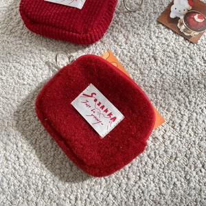 Macro shot of red plush coin purse featuring a white brand label and silver metal ring