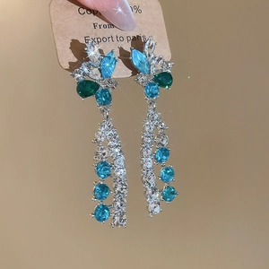 Detailed macro view of French style floral earrings with blue and green zircons in copper