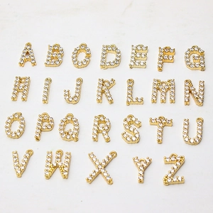 Detailed flat lay of 26 gold-plated letter pendants with sparkling micro-pave zirconia