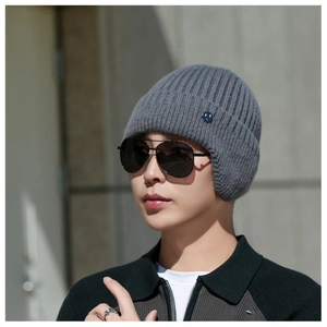Close-up of grey knit beanie earflaps with blue smile button detail and thick texture