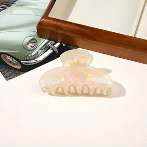 Close-up of a pearlescent cream hair claw clip with shell texture on a vintage backdrop