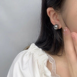 Close-up of grey Baroque pearl earring with metallic luster on model's ear