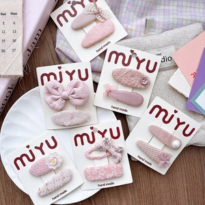 Detail of pink fabric bow hair clips with lace, floral patterns and pearl accents