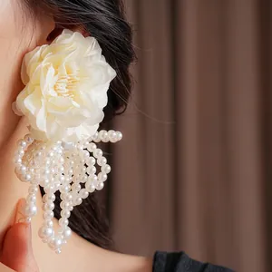 Elegant off-white fabric flower earrings with long pearl tassels shown on model
