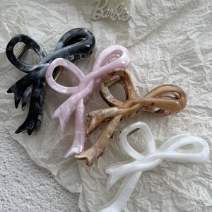 Detailed view of four acetate hair claws with butterfly bow design in marbled patterns