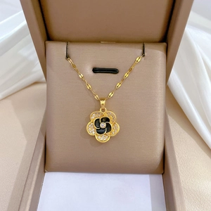 Elegante gouden titanium stalen bloemenketting met zwart-witte bloemblaadjes in een doosje