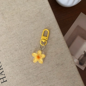 Detailed view of yellow transparent resin flower keychain on a beige linen book background