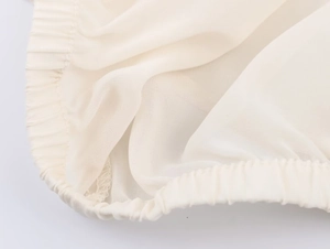 Detailed macro view of beige georgette fabric showing ruffled elastic and fine stitching