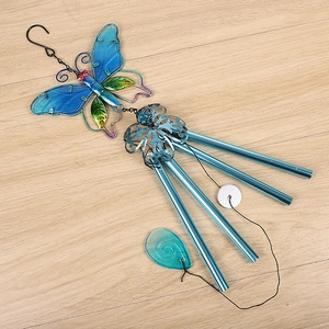 Close-up of blue butterfly wind chime with glass wings and four metallic tubes on wood
