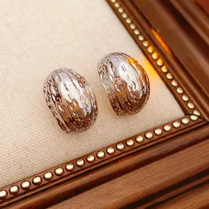 Silver geometric C-shape earrings with liquid metal lava texture on beige fabric