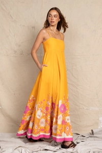 Detail of floral print and pink hem on a yellow spaghetti strap vacation maxi dress