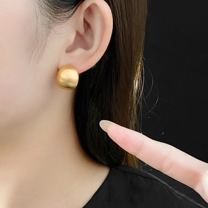 Nahaufnahme minimalistischer vergoldeter runder Ohrstecker am Model mit schwarzem Grund