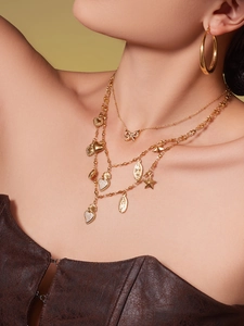Detailed view of layered gold necklaces with crystal heart, star, and bow pendants on model
