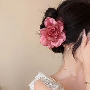Detailed view of a large pink gradient fabric rose hair clip elegantly worn in a hair bun