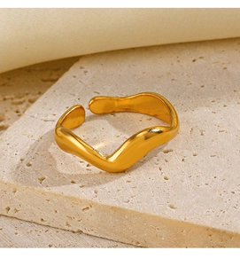 Detailed view of the gold-plated wavy irregular ring on a textured stone surface