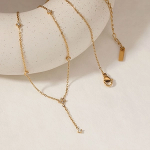 Elegant gold Y-shaped necklace with zircon flowers draped on a ceramic prop