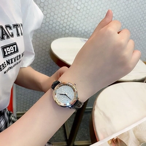 Elegant rose gold watch with full diamond dial on a model's wrist in a cafe setting