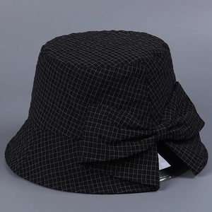 Vue détaillée d'un chapeau cloche noir à carreaux avec un grand nœud décoratif sur le côté