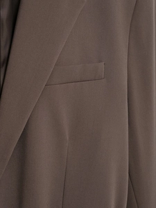Detailed macro view of brown blazer lapel and front pocket with woven fabric texture