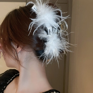 Detail view of feather hair claw clip with silk ribbon worn by a model in soft lighting