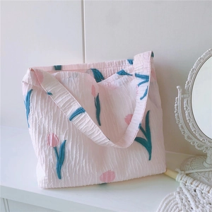 Détail de la broderie de tulipes roses sur le tissu en toile texturée du sac à main