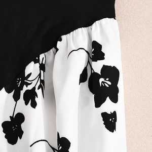 Gros plan sur l'imprimé floral contrasté et le tissu sergé noir d'une robe longue dos nu