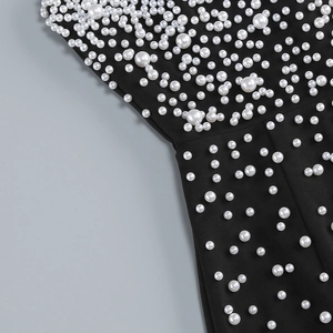 Detailed close-up of white faux pearls hand-beaded on black elastic knit party dress fabric