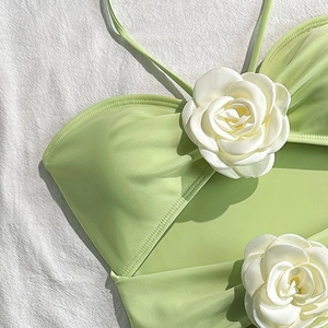 Close-up of light green bikini top featuring elegant 3D white camellia flower details