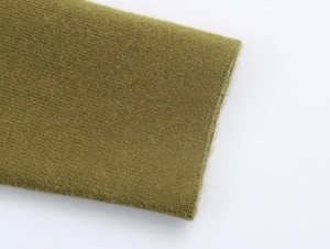 Dettaglio dei polsini in maglia verde che mostra la trama fine e la qualità del tessuto