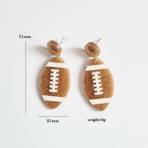 Glittery gold football acrylic earrings with 51mm length and 21mm width measurements