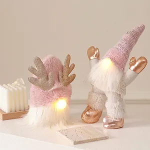 Glow pink Christmas gnomes with golden antlers and warm LED lights on stone base