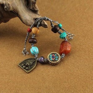 Detail of Tibetan-style bracelet with carved metal plate, turquoise beads, and eye motif