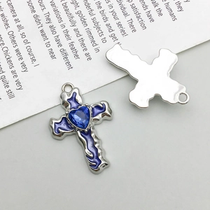 Macro detail showing front and back of silver cross pendant with blue heart crystal