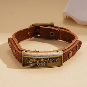 Detail of vintage brown leather bracelet with bronze plaque and engraved quote for women